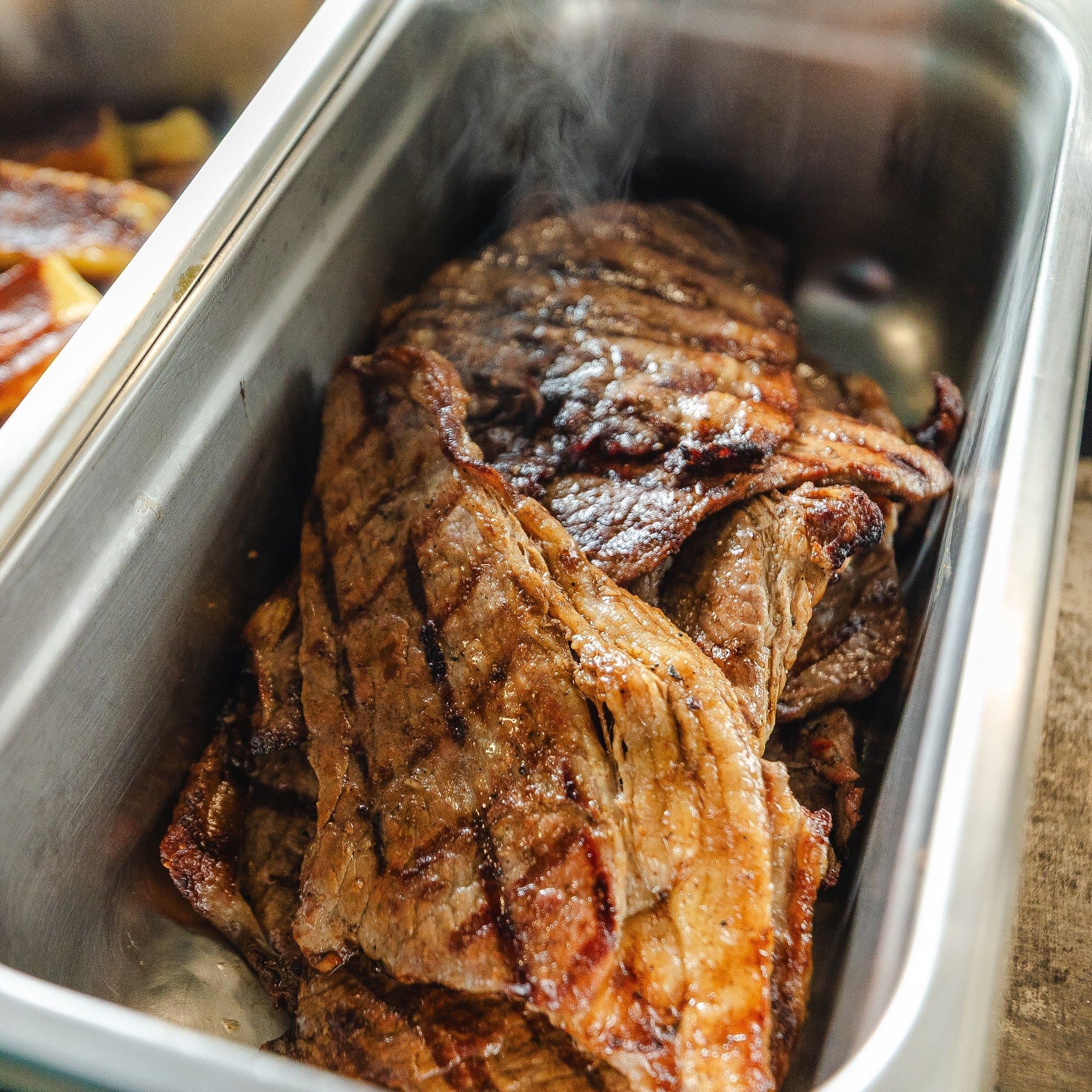 Carnes grelhadas fumegantes servidas no grill do Labuka